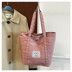 Detalle del bolso tote de nailon rosa con etiqueta de moda y cierre de botón metálico
