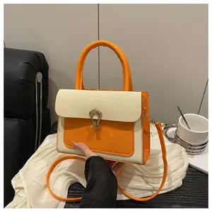 Detail of color-block handbag featuring orange leather, woven texture, and horseshoe buckle