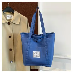 Detalle de bolsa de pañales de nailon azul marino con etiqueta sobre fondo de gabardina