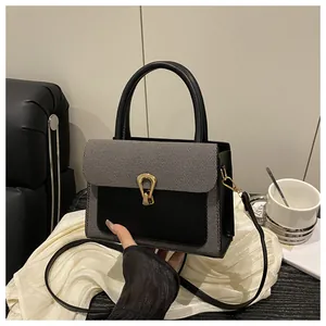 Detail of grey fabric flap and black leather bag with golden horseshoe twist lock closure