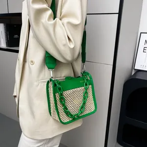 Close-up of green leather and woven straw crossbody bag with thick chain handle detail