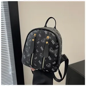 Close-up of black mini backpack featuring white bear motifs and litchi texture
