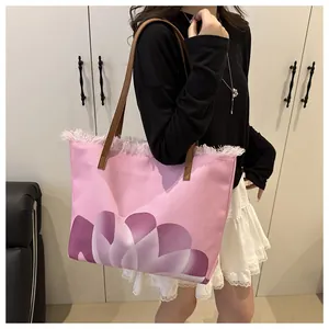 Detalle del bolso tote de lona rosa con estampado de flores púrpuras y asas de cuero