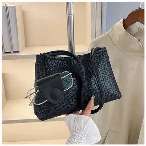 Detail of black woven shoulder bag with unique leather glasses holder attachment