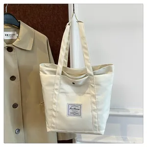 Detalle de un bolso tote de nailon crema con parche de moda, bolsillo frontal y botón