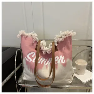 Detail of pink canvas beach tote with fringe trim, leather straps and Summer lettering