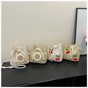 Detail view of woven straw bucket bags with drawstring closure and floral cherry decor