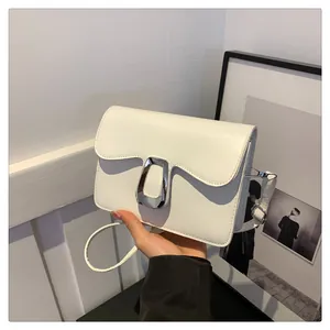 Detail of white square bag with wavy flap edge and silver metallic buckle closure