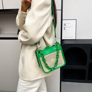 Detail of green and white woven crossbody bag with chunky chain and gold lettering