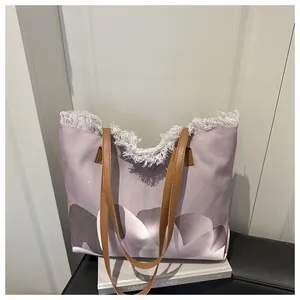 Detalle de bolso tote de lona con estampado degradado morado y bordes deshilachados