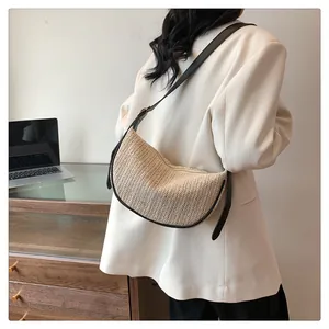 Detail of hand-woven beige crescent crossbody bag with adjustable brown leather strap