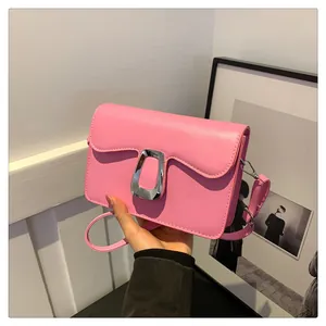 Close-up of a pink leather crossbody bag with a distinctive silver metallic buckle