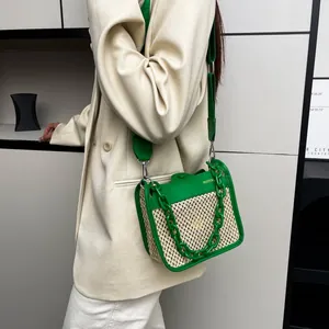 Detail of green leather and straw woven crossbody bag with chunky chain accent