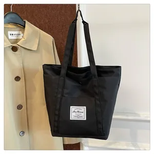 Detalle de un bolso tote de nailon negro con parche de moda y cierre de presión