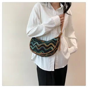 Detail of half-moon bag featuring colorful wave-pattern knit and adjustable leather strap