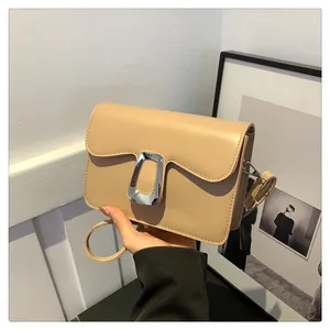 Detail view of beige square shoulder bag featuring a rectangular silver metal clasp