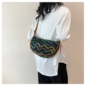 Detail of hand-woven crescent bag with wave patterns and leather strap on model