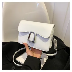 Close-up of white crossbody bag with wave edges and silver metallic clasp