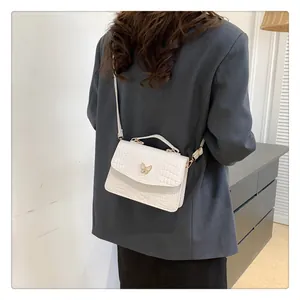Close-up of white butterfly buckle shoulder bag with elegant crocodile texture on shoulder