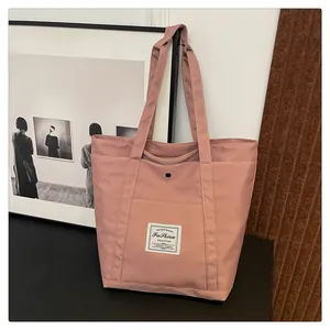 Vista detallada del bolso tote rosa de nailon con bolsillo frontal y parche blanco