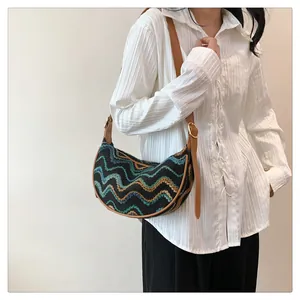 Detail of multi-color woven crescent bag with retro wave patterns and leather strap