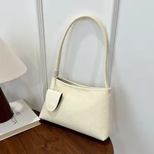 Elegant off-white woven tote shoulder bag with a small matching pouch on a wooden table