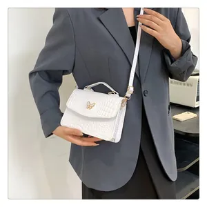 Detailed view of white crocodile texture handbag with gold butterfly buckle on grey blazer