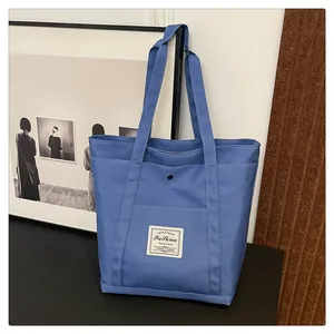 Detalle del bolso tote de nailon azul que muestra el bolsillo frontal con botón metálico