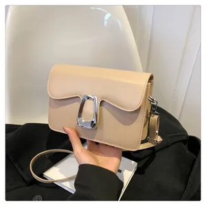 Detail of cream leather crossbody bag featuring a modern oversized silver trapezoid buckle