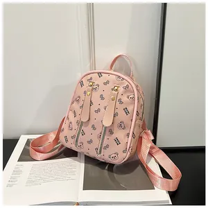Detail of pink mini backpack with bear pattern, gold studs, and textured PU material