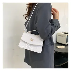 Detail showing white crocodile texture leather handbag with golden butterfly clasp on model
