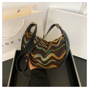 Close-up of brown wool shoulder bag featuring colorful wave embroidery and gold metal rings
