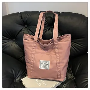 Detalle de bolso tote de nailon rosa Morandi con bolsillo frontal y botón a presión