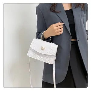 Detailed view of white crocodile pattern bag with gold butterfly clasp and round handle