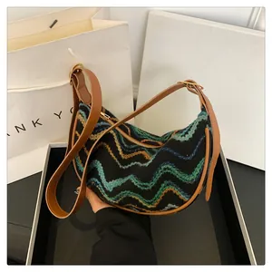 Detail showing the woven colorful hobo bag with zigzag patterns and leather strap