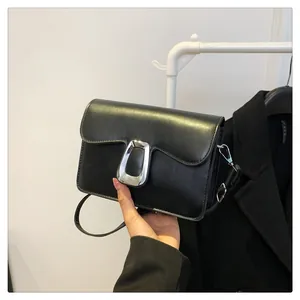 Close-up of black crossbody square bag with a silver metal trapezoid buckle detail