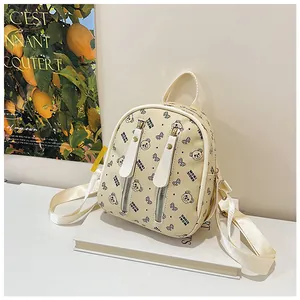 Mini cream backpack with black bear patterns and vertical zippers on a white book