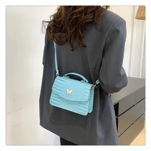 Detail of light blue crocodile-embossed leather handbag with gold butterfly clasp