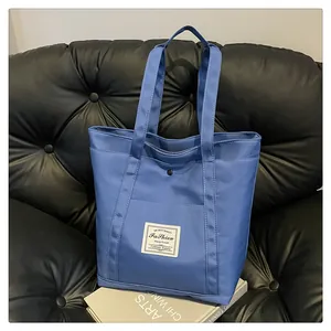 Primer plano del bolso tote de nailon azul con bolsillo frontal y cierre de botón metálico