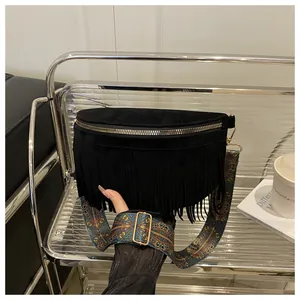 Detailed view of black suede fringe crossbody bag with retro patterned strap and metal zipper.