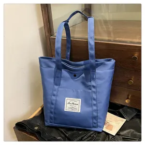 Bolso tote de nailon azul con parche de Fashion y bolsillo frontal sobre fondo oscuro