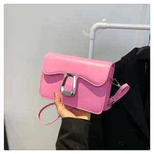 Detailed view of pink rectangular shoulder bag with wavy edge flap and silver metal lock