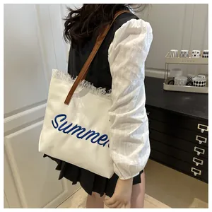 Dettaglio della borsa tote bianca con ricamo Summer blu e bordi con piccole frange