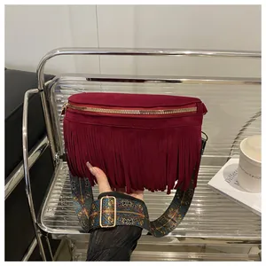 Detailed view of burgundy suede fringe crossbody bag with colorful ethnic strap and gold hardware.