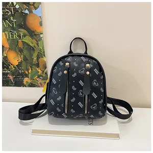 Detail view of mini black backpack with bear prints and golden zipper pockets on books