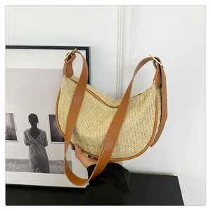 Detail of woven straw hobo bag with beige V-pattern texture and brown leather strap