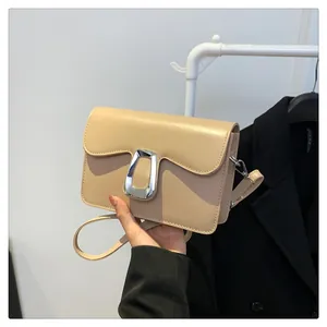 Detail of beige faux leather square bag with large silver U-shaped metal buckle and strap