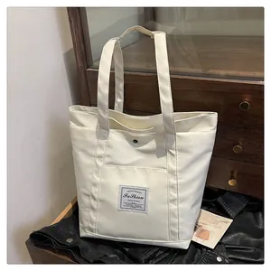Primer plano de bolso tote de nailon marfil con bolsillo a presión y etiqueta de moda