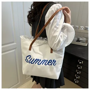 Dettaglio della borsa tote in tela bianca con ricamo Summer e finiture con frange