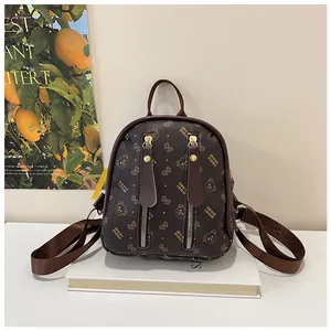 Close-up of brown mini backpack with bear pattern and golden zipper details